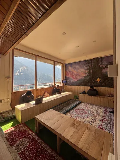 Café lounge with wooden seating, rugs and large windows facing the mountains